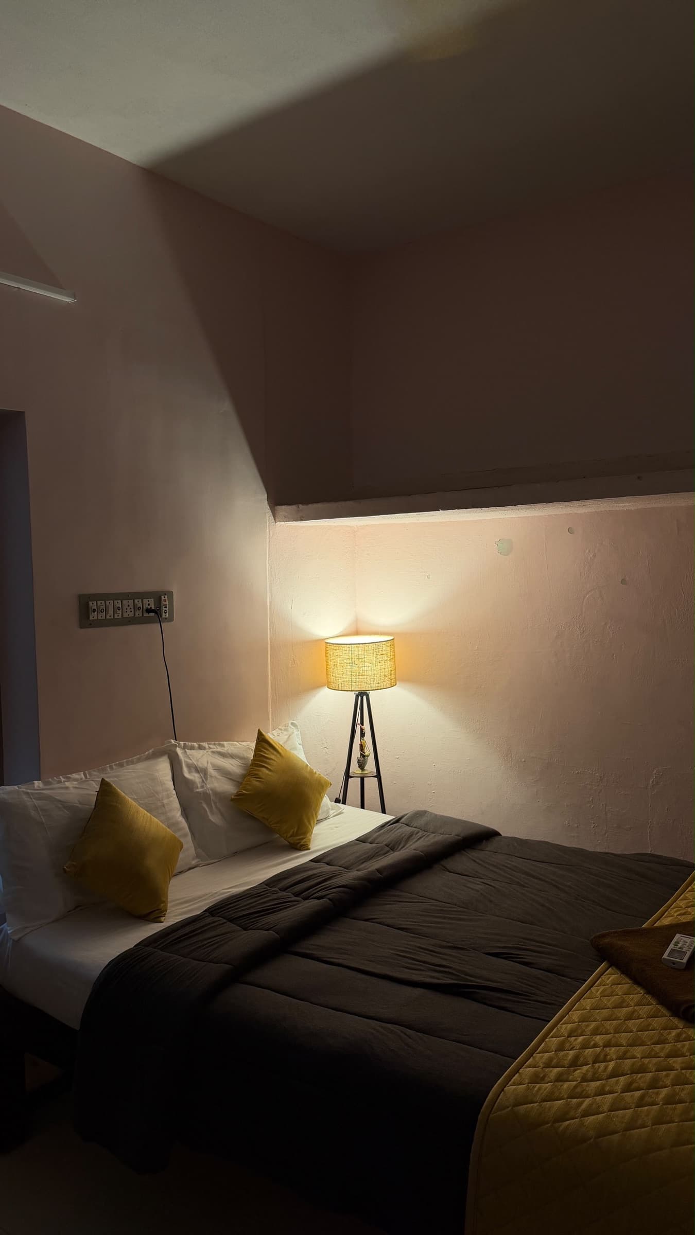 Mustard-accented bedroom in the soft glow of a tripod floor lamp